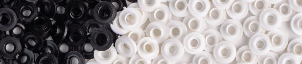 Stos czarnych i białych nitów i tulejek plastikowych