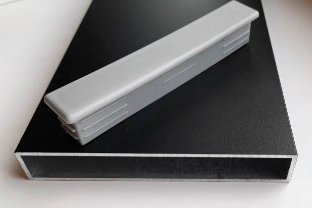 Plastikowa zatyczka do profili aluminiowych o wymiarach 120mm x 20mm, wykonana z polietylenu leżąca na przykładowym profilu